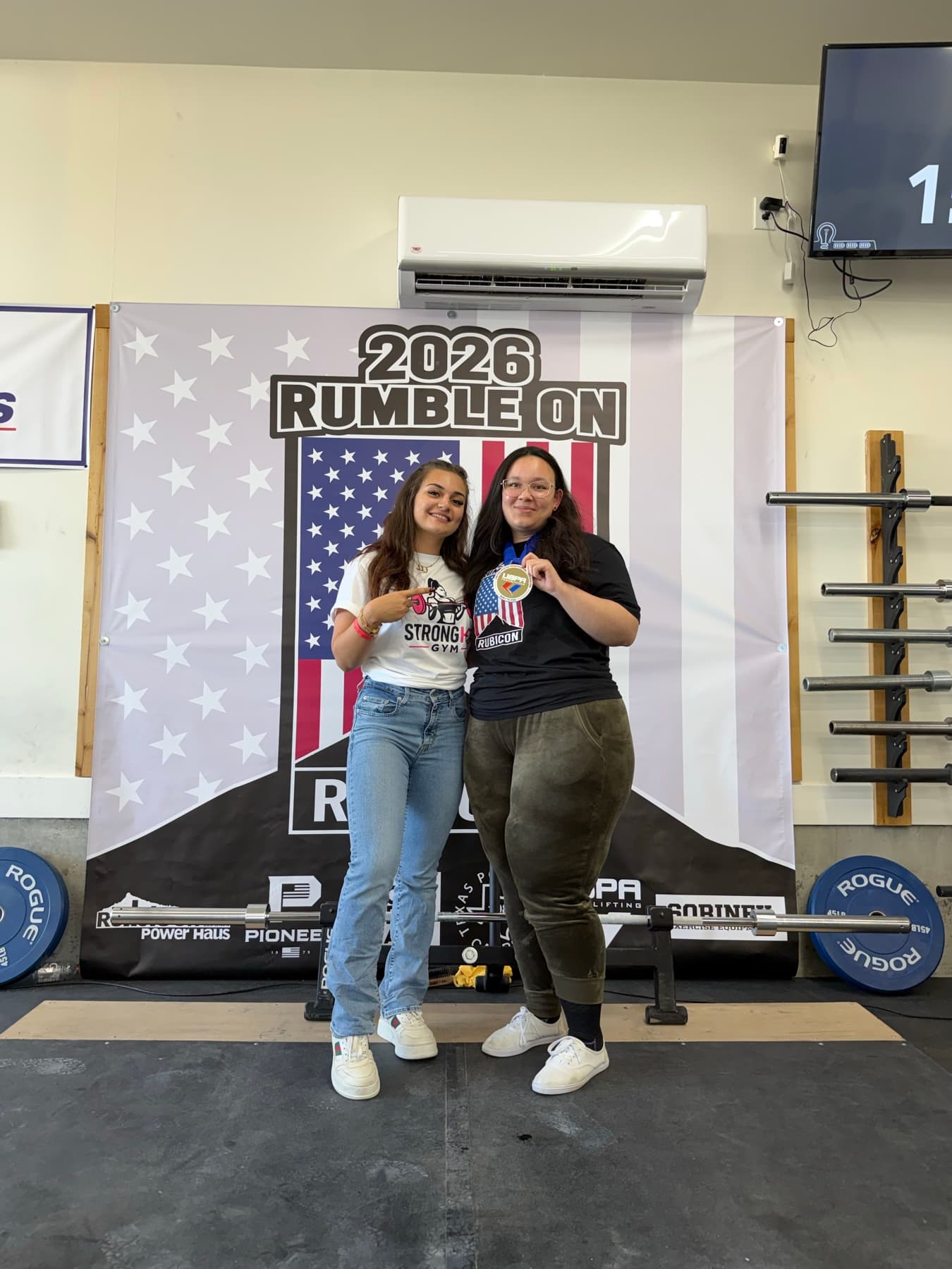 Rand celebrating with a powerlifting client holding her competition medal