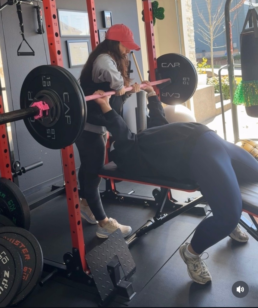 Rand spotting a client during bench press at StrongHER Gym